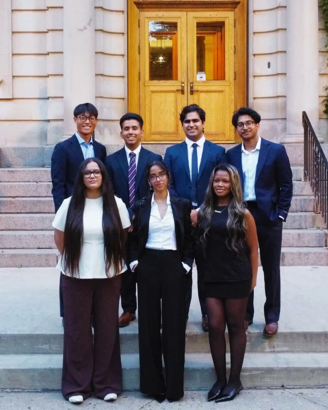 The ESA executive team — seven students in formal dress on the steps of a campus building